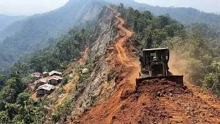 Thumbnail: Epic Mountain Road Building: Bulldozer Clearing Red Soil Near Poor Village.